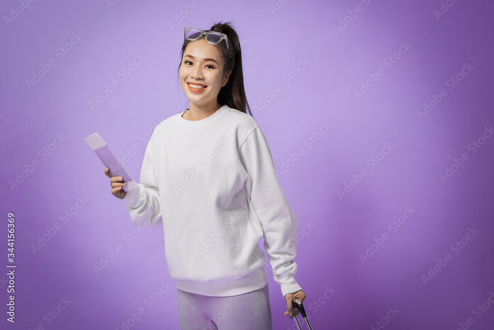 portrait of happy young woman going on vacation with passport and her suitcase over a violet background portrait of happy young woman going on vacation with passport and her suitcase over a violet background