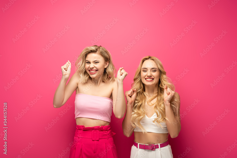Happy blonde women showing yeah gesture on pink background Happy blonde women showing yeah gesture on pink background