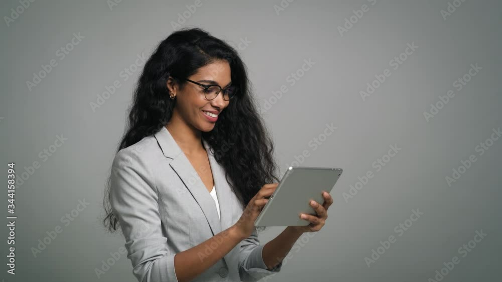 Young smiling businesswoman uses a digital table in studio shot. Shot with RED helium camera in 8K. Young smiling businesswoman uses a digital table in studio shot. Shot with RED helium camera in 8K.