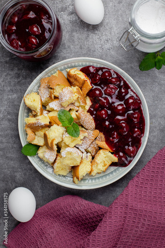 Kaiserschmarren or Kaiserschmarrn is a traditional Austrian or German sweet pancake dessert, with icing sugar and berry, cherry sauce or rote grutze jam. Top view.  photo