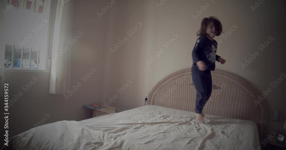Niña soriente saltando sobre la cama