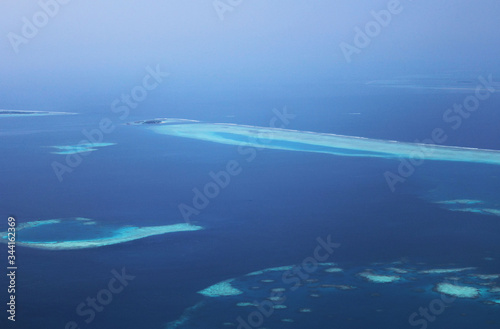Aerial view of tropical islands and atolls in Maldives. View from, airplane. Sea island located in Maldives in area of North atoll. White sand beach with blue lagoon sea. Beautiful exotic resort hotel