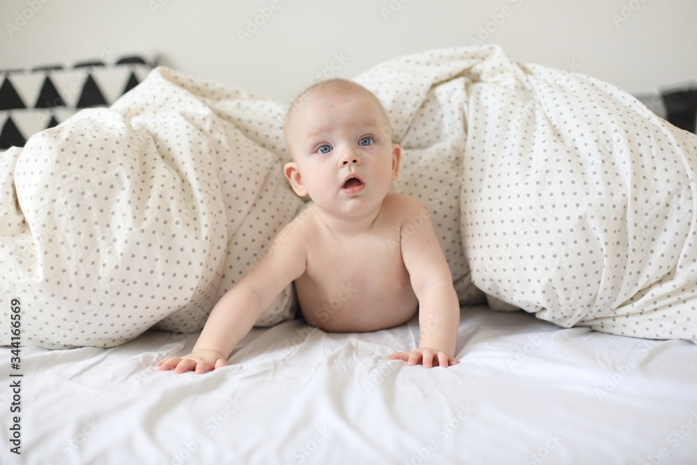 Little child doing tummy time. Adorable baby learning to crawl in white bedroom. Cute funny baby lying on bed. Little child doing tummy time. Adorable baby learning to crawl in white bedroom. Cute funny baby lying on bed.