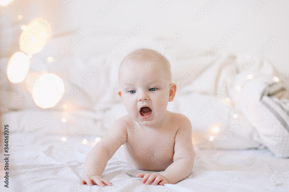 Little child doing tummy time. Adorable baby learning to crawl in white bedroom. Cute funny baby lying on bed. Little child doing tummy time. Adorable baby learning to crawl in white bedroom. Cute funny baby lying on bed.