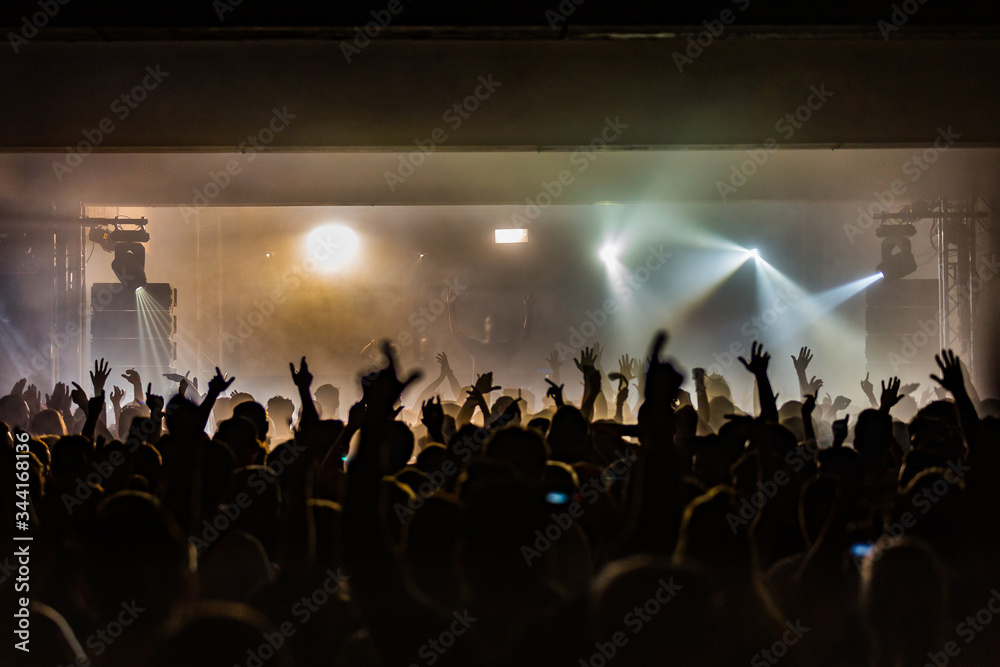 Crowd silhouette at dance event with hands in the air concert with a DJ performing