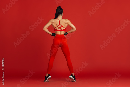 Ideal body. Beautiful young female athlete practicing in studio, monochrome red portrait. Sportive fit brunette model training. Body building, healthy lifestyle, beauty and action concept. © master1305