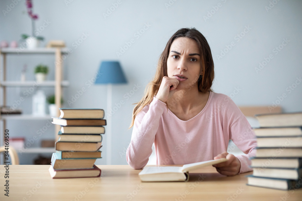 Female student sits at a table with books preparing for exams. Female student sits at a table with books preparing for exams.