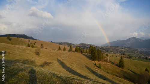 

Rainbow over stormy sky. Rural landscape with rainbow over dark stormy sky in a countryside at spring day. 