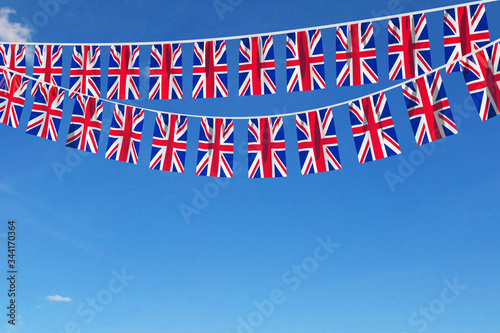Fototapeta United Kingdom flag festive bunting hanging against a blue sky. 3D Render