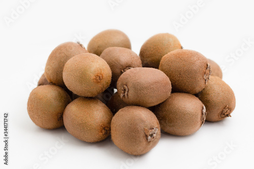 Pile of whole brown kiwi fruits isolated on white background. Bunch of hairy fresh ripe kiwifruits. Agriculture or organic food concept