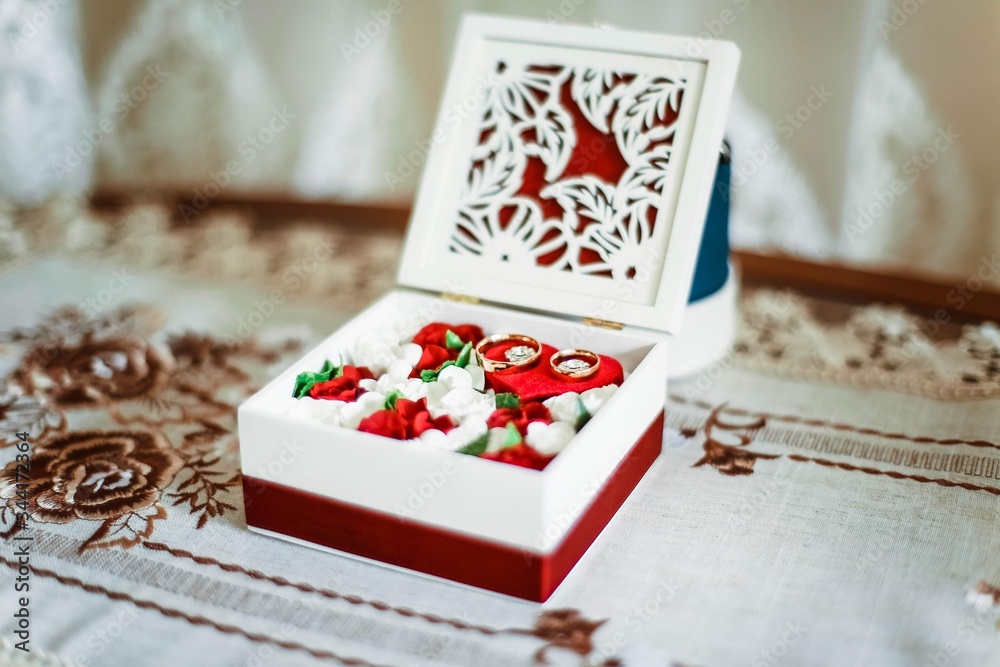 Obraz premium Gold wedding rings on a background of flowers. Wedding ring for the bride and groom on their wedding day. A pair of wedding rings.