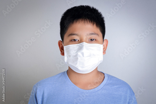 An Asian boy wears a mask, covering his mouth and nose, preventing coronavirus. And dust, pm 2.5. Children's health concept © SUPERMAO