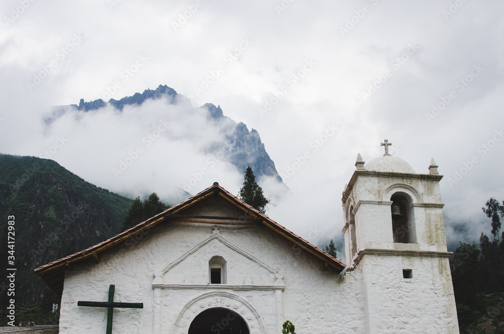 Iglesia con montañas y nubes al fondo en un pueblo 