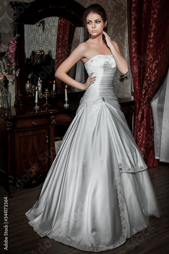 Elegant brunette bride is in full growth in a luxury room with columns