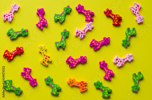 Photography Toy giraffes on yellow background. Colorful wooden giraffes.
