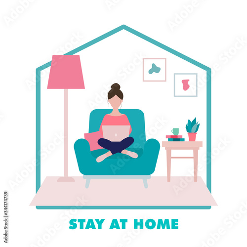 Stay at home concept.Woman sitting on an armchair with laptop  in her living room in period of self isolation and social distancing during COVID-19 virus epidemic. Freelance or studying concept.