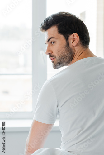 Back view of man looking away near window at home