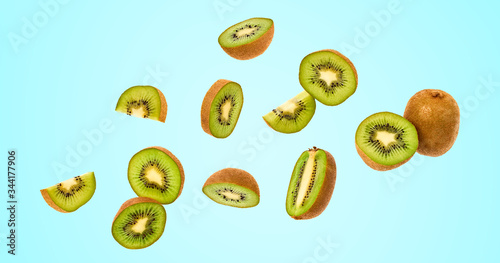 Fresh kiwi fruit flying in air on blue. Fruity green color diet food. Summer whole, cut kiwi background. Colorful levitation concept. Falling fly kiwi, fruity creative vivid design