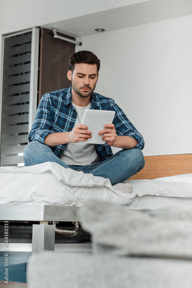 Selective focus of man with crossed legs using digital tablet on bed Selective focus of man with crossed legs using digital tablet on bed