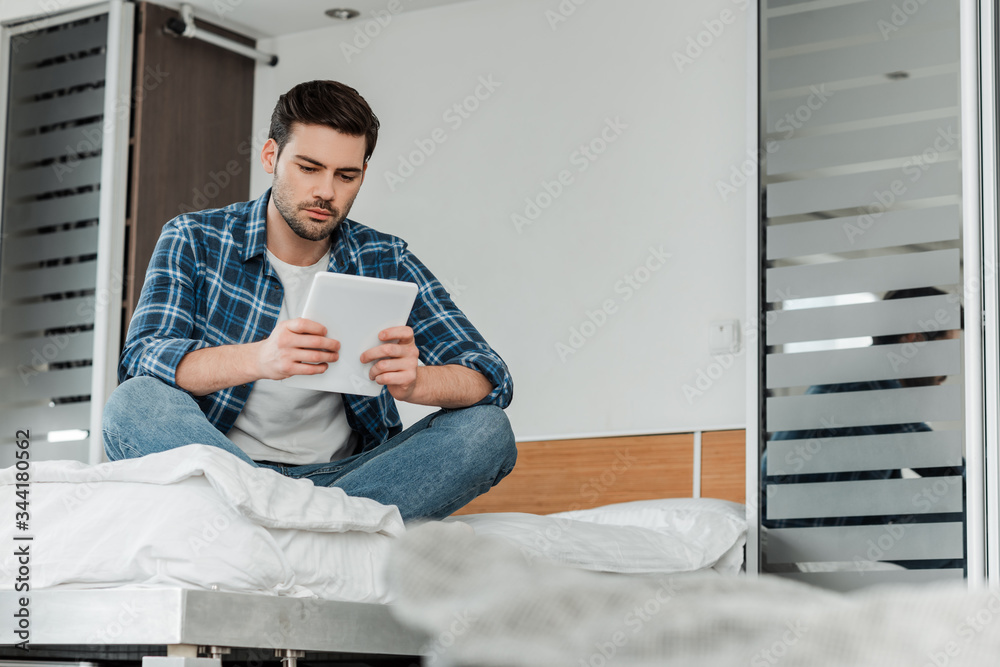Selective focus of man in plaited shirt using digital tablet on bed at home Selective focus of man in plaited shirt using digital tablet on bed at home