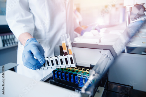 фотографія Medical worker in laboratory places blood sample for examination in automatic analyzer