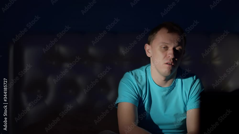 The guy is watching a shocking program on TV late at night The guy is watching a shocking program on TV late at night