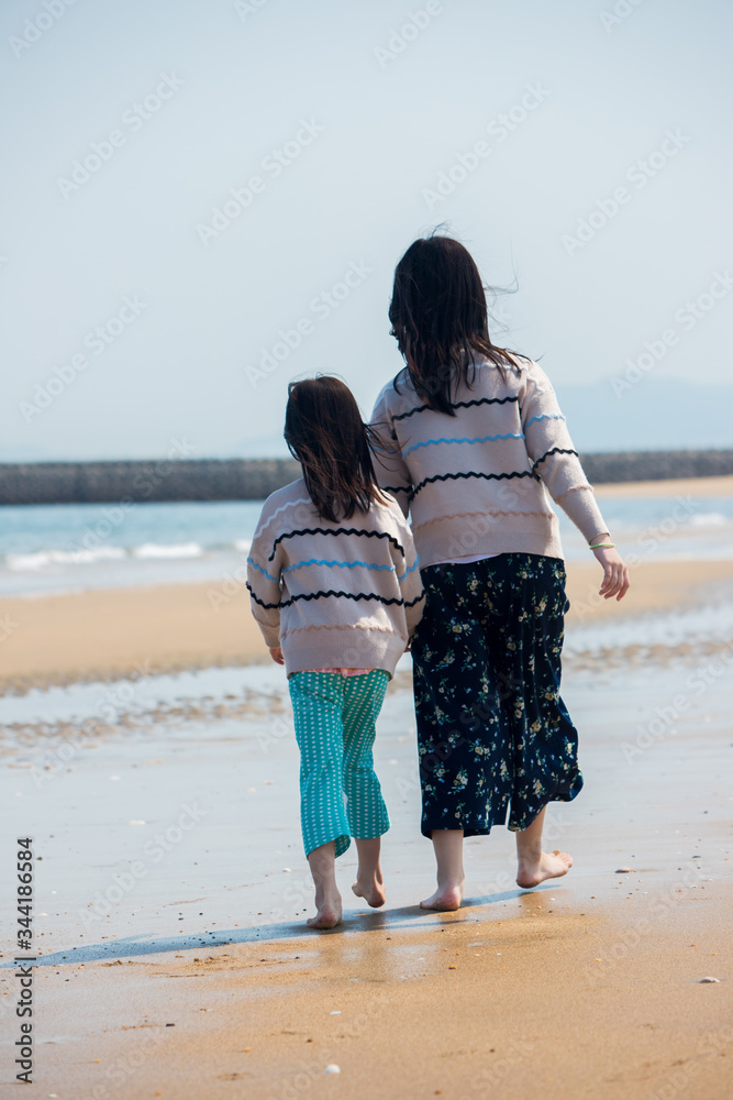初夏の海で砂遊びをしている子供姉妹