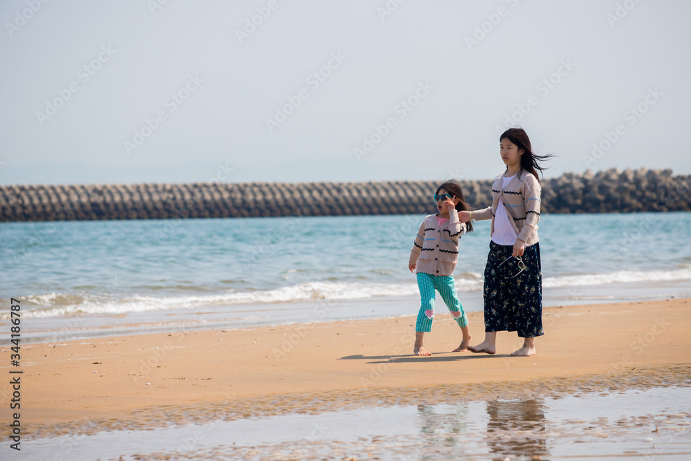 初夏の海で砂遊びをしている子供姉妹