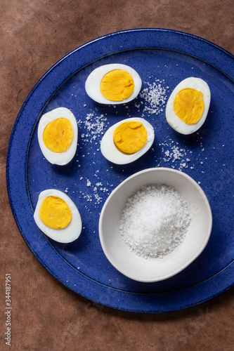 fife half boild eggs on a blue plate with rock salt