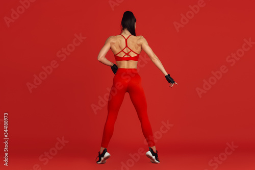 Posing graceful. Beautiful young female athlete practicing in studio, monochrome red portrait. Sportive fit brunette model training. Body building, healthy lifestyle, beauty and action concept.