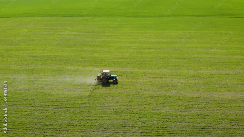 Aerial view of tractor spraying wheat or barley field. Spring agronomic activity on agricultural land Aerial view of tractor spraying wheat or barley field. Spring agronomic activity on agricultural land