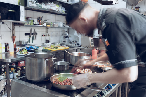 Behind the scenes of brands. The chef cooking in a professional kitchen of a restaurant meal for client or delivery. Open business from the inside. Meals during the quarantine. Hurrying up  motion.