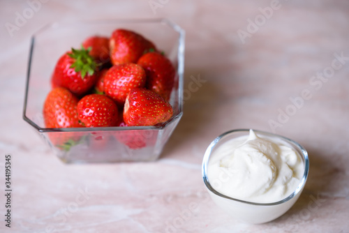 Strawberries on a transparent plate and cream on a transparent plate