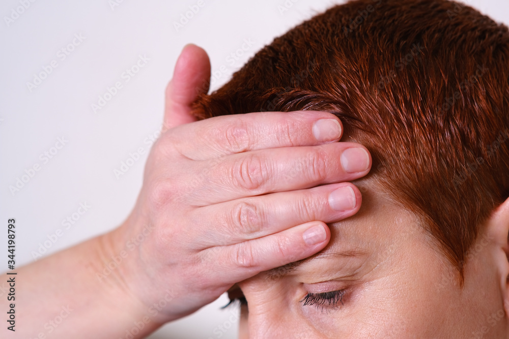 The woman put her hand to her forehead, experiencing a headache. Migraine, fever, blood pressure. Symptom of disease.