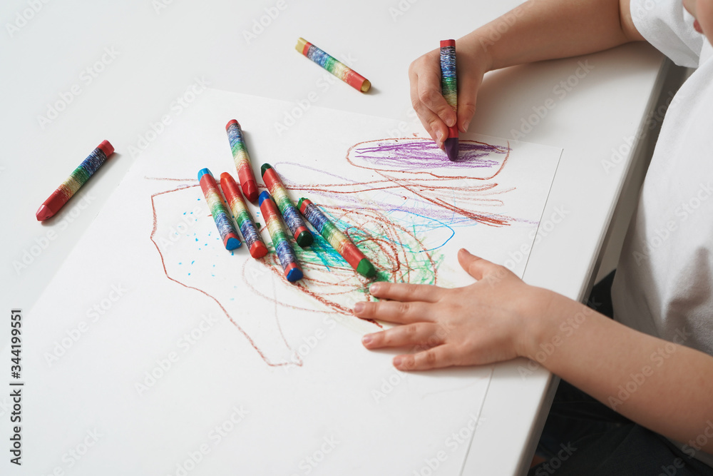 The child draws with wax crayons on paper. Close-up process of children ...