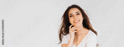 Beauty fashion portrait of smiling sensual asian young woman with dark long hair in white shirt on white background banner