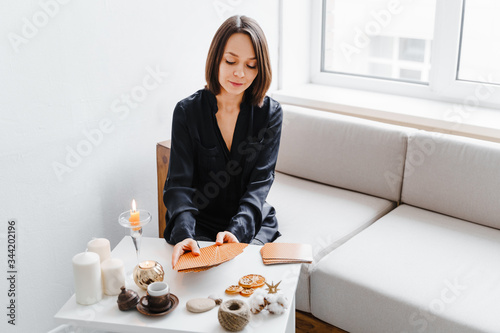 Foto Woman is reading metaphorical or Tarot cards on the table in home office