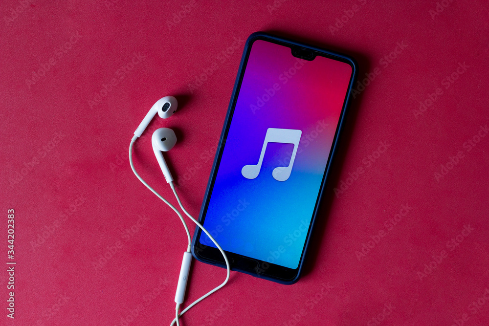 Close-up of smart phone with headphones on a red background. (Top view). Listen to music.