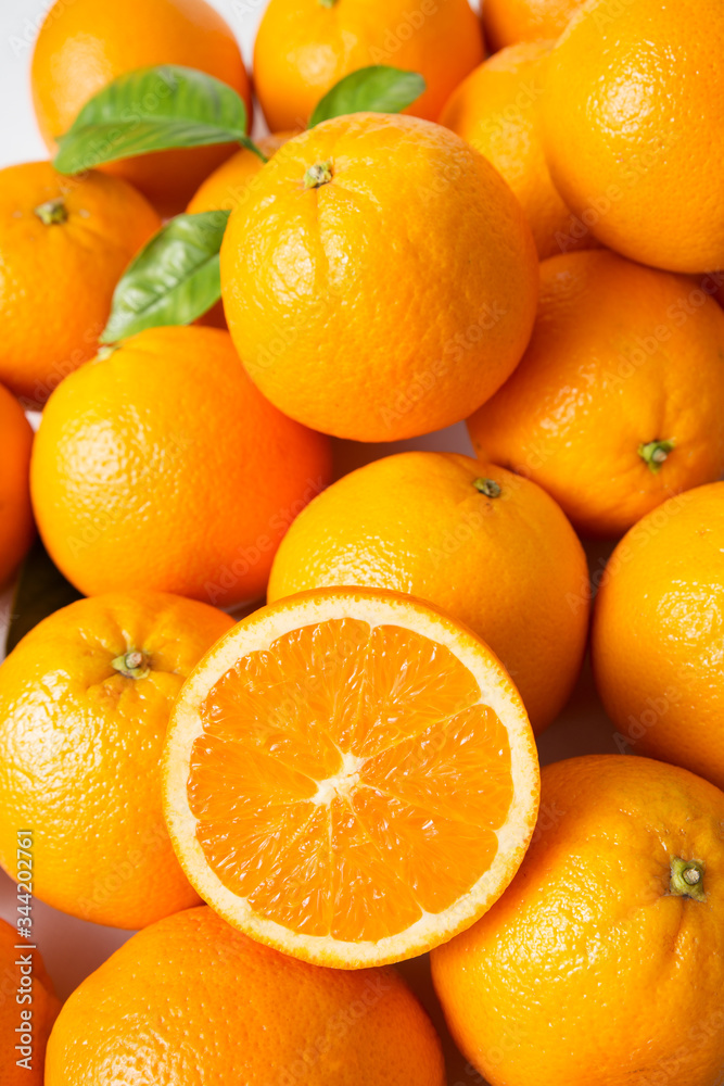 Heap of bright fresh juicy orange fruits with green leaves. Closeup, top view, vertical shot. Natural vitamin or organic food concept Heap of bright fresh juicy orange fruits with green leaves. Closeup, top view, vertical shot. Natural vitamin or organic food concept