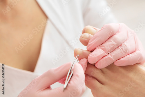 Professional pedicure using special nail intrument.Patient visiting podiatrist.Medical pedicure procedure using tweezer.Foot treatment in SPA salon.Podiatry clinic.