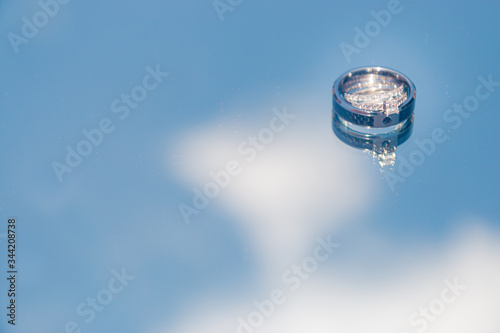 Wedding rings on a reflected blue sky background