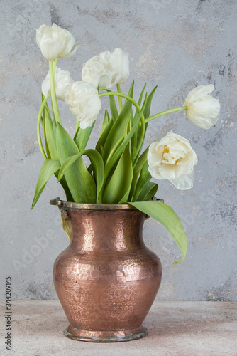 White tulips in old copper vase photo