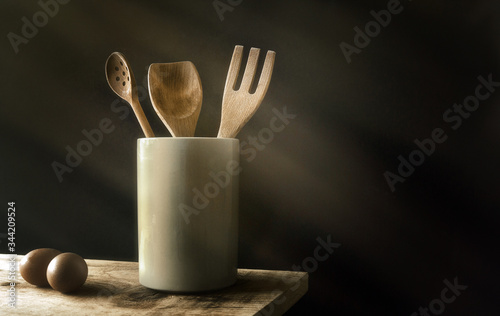 Kitchen wooden utensils set and eggs on wooden table low key photography cooking preparation