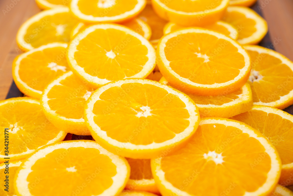 Close-up view of many orange slices laying on wooden desk. Bright summer citrus fruits. Side view. Studio shot. Nutrition and vegetarian concept Close-up view of many orange slices laying on wooden desk. Bright summer citrus fruits. Side view. Studio shot. Nutrition and vegetarian concept