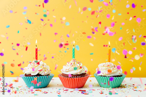 Birthday cupcakes with confetti on yellow background
