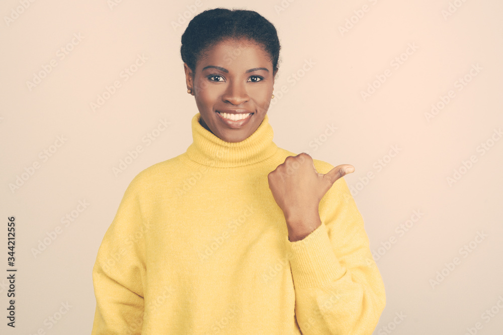 Content young woman pointing at copy space. Beautiful cheerful young African American woman pointing away and smiling at camera. Promotion concept Content young woman pointing at copy space. Beautiful cheerful young African American woman pointing away and smiling at camera. Promotion concept