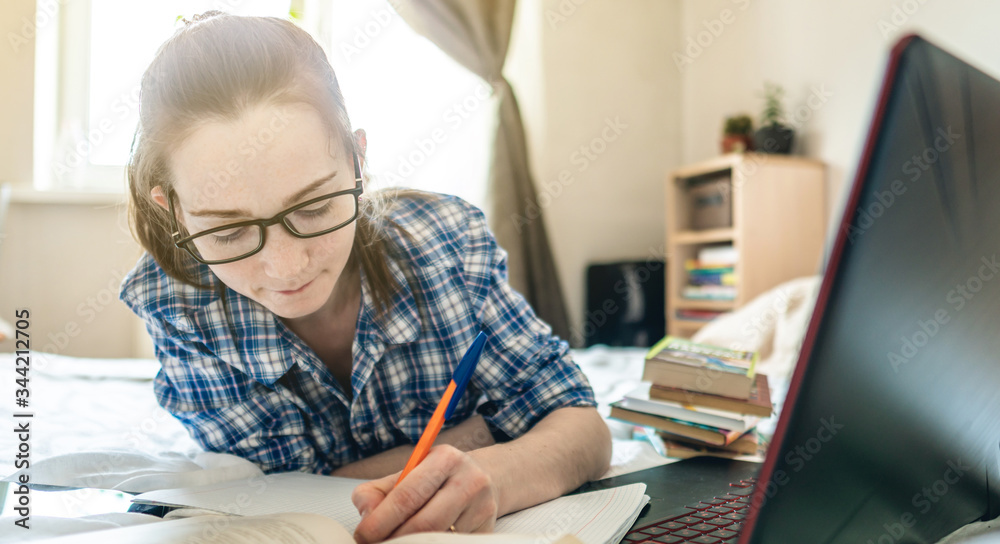 Student is passing online lesson on the Internet at home lying on a bed. Remote learning in schools and universities Student is passing online lesson on the Internet at home lying on a bed. Remote learning in schools and universities