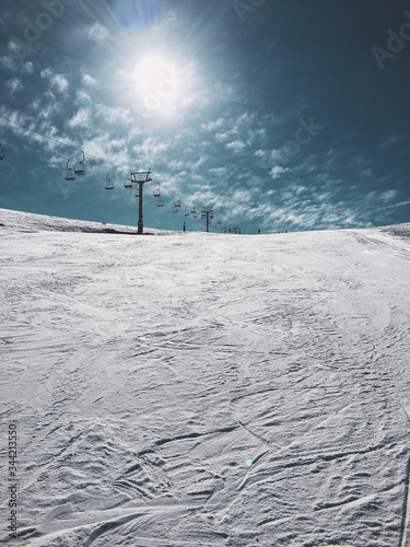 mountain top with snow, sky, clouds, ski-run and ski lift
