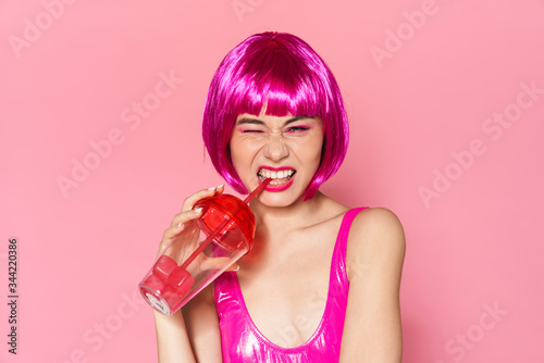 Image of young party girl wearing wig smiling and drinking beverage