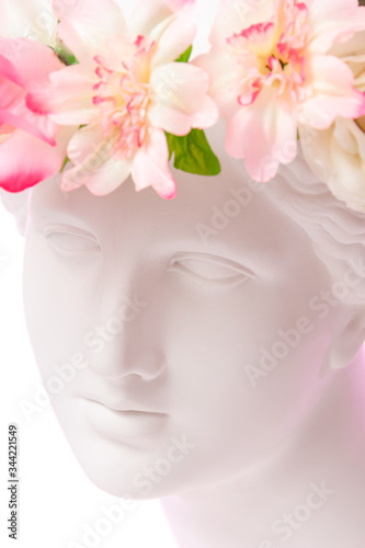 Beautiful young female white face and colorful flowers. Plaster antique bust of Venus in a floral wreath. Beauty spring and summer model girl with fresh bouquet. © Ded Pixto